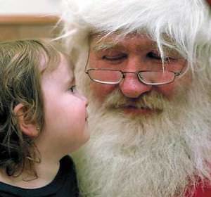 Santa Claus with young child Riley Whelan, 2, and Larry Geiger as Santa contemplate each other last week at the United Way office.